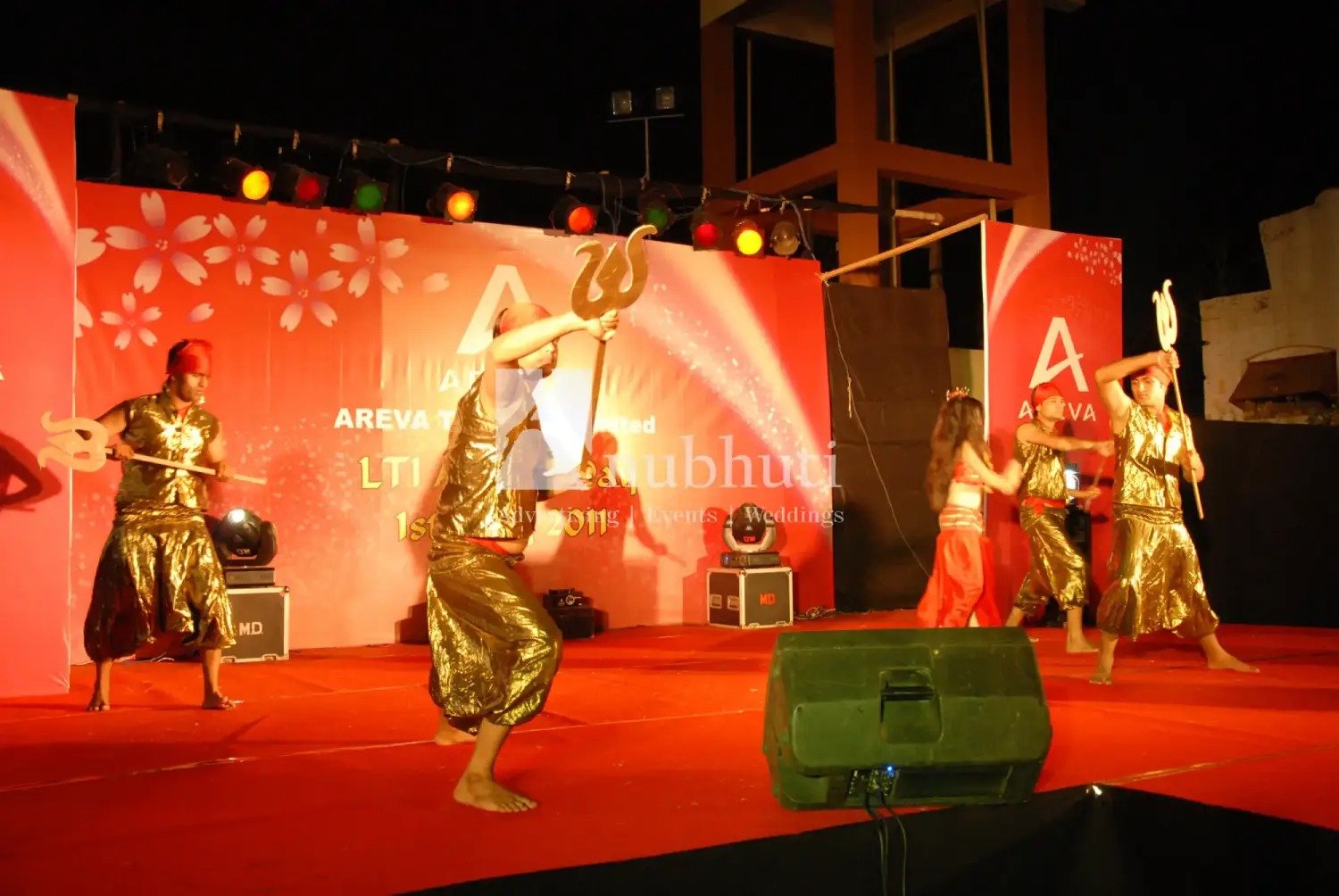Man and woman speaking on stage at night with blue lighting
